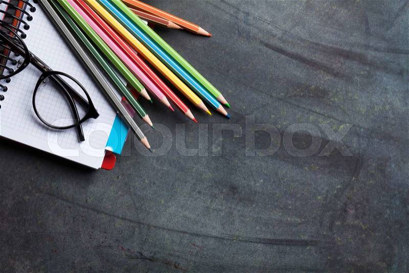 Notepads and supplies over chalk board. Back to school concept with copy space, stock photo