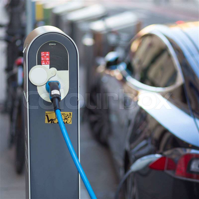 Power supply for electric car charging. Electric car charging station. Close up of the power supply plugged into an electric car being charged, stock photo