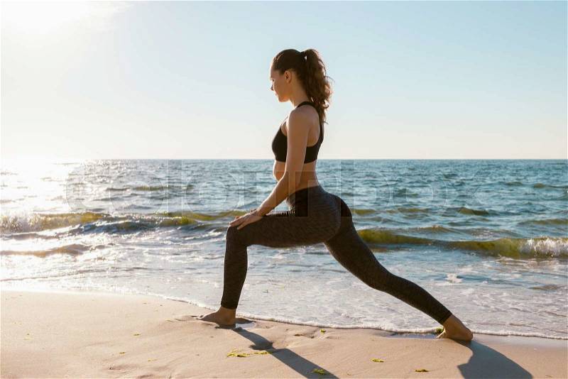 Sport girl on a beach doing lunges exercises. Concept of of a healthy lifestyle, stock photo