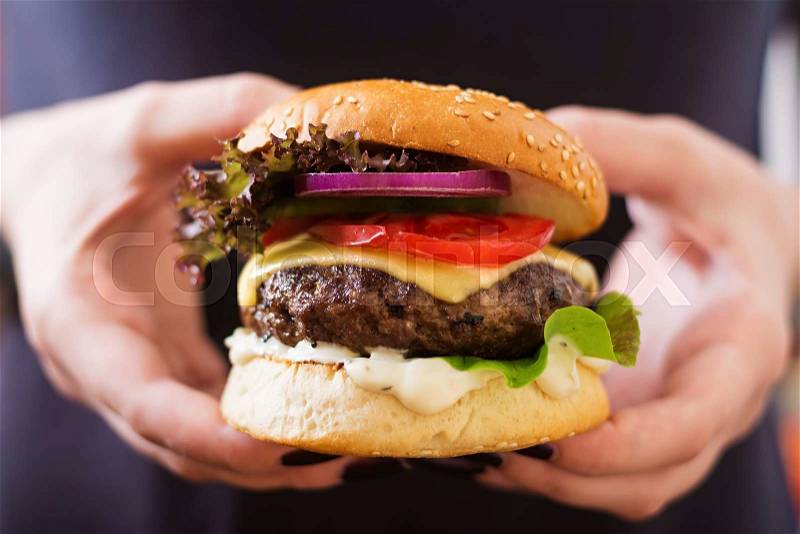 Big sandwich - hamburger burger with beef, cheese, tomato and tartar sauce in female hands, stock photo