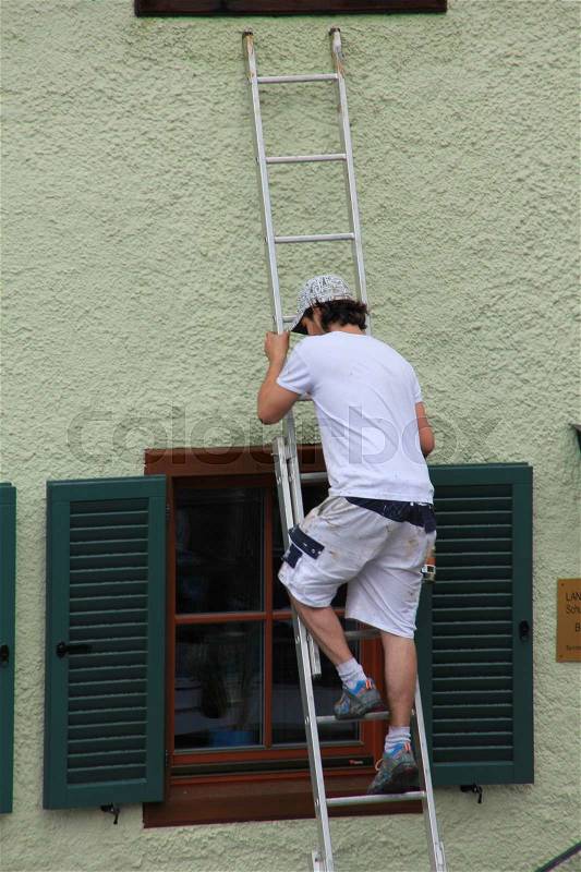 The craftsman is going down from the step-ladder in the summer in Austria, stock photo