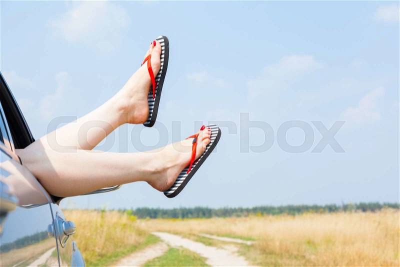 Female legs dangling from the open car window in the shales, stock photo