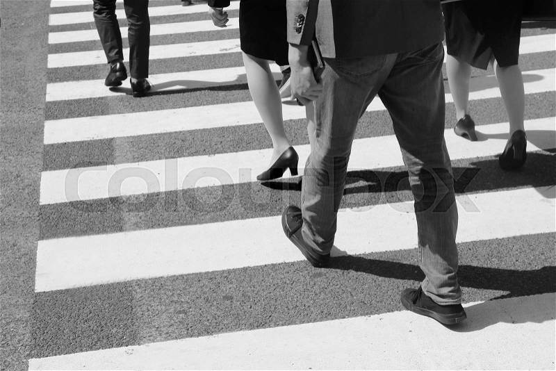 Close-up on unidentified people legs crossing street, stock photo