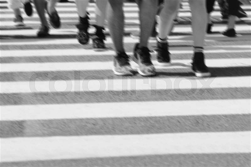 Close-up on unidentified people legs crossing street, stock photo