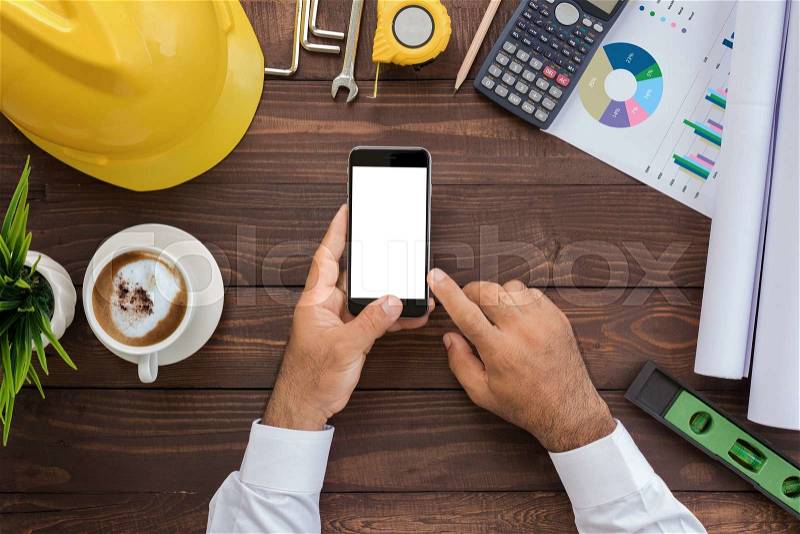 Engineering using phone on his workspace top view, stock photo