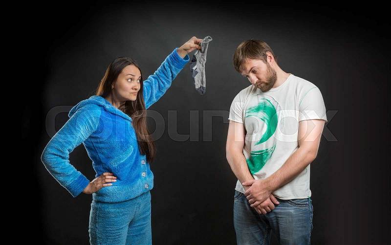 Disgusted woman holding a dirty sock of her husband, stock photo