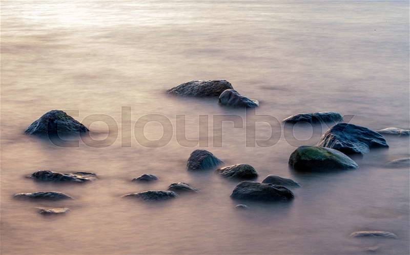 Sea mist around rocks during cloudy sunset, stock photo