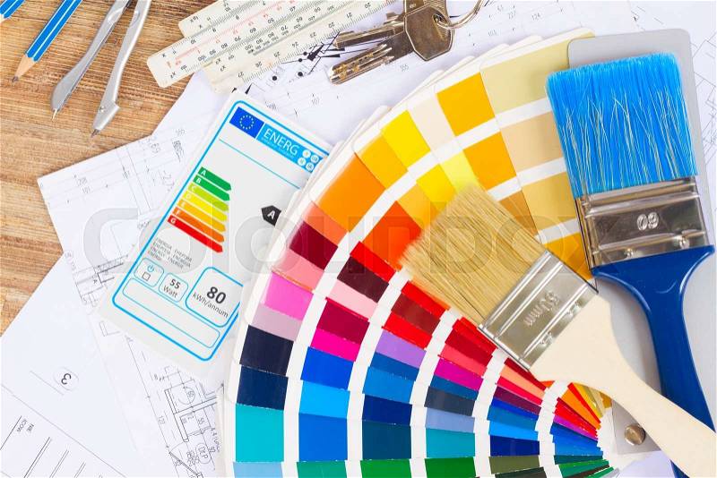 Interior designer\'s working table with energy rating chart, keys, architectural plan of the house, color palette and brushes, stock photo