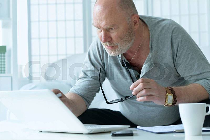 Mature businessman working with laptop in office, stock photo