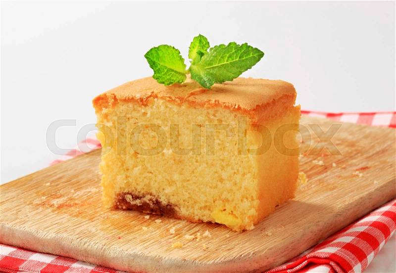 Slice of homemade sponge cake on wooden cutting board, stock photo