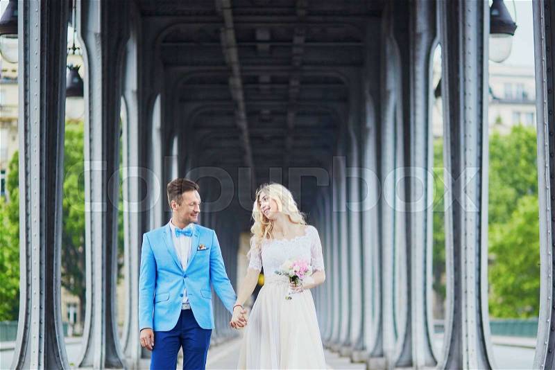 Just married couple in Paris, France. Beautiful young bride and groom on Bir-Hakeim bridge. Romantic wedding concept, stock photo