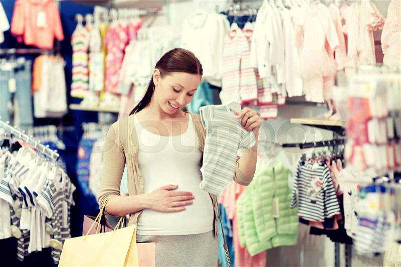 Pregnancy, people, sale and expectation concept - happy pregnant woman with shopping bag buying baby bodysuit at children clothing store, stock photo