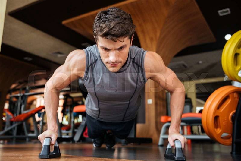 Man athlete training and doing push-ups in gym, stock photo