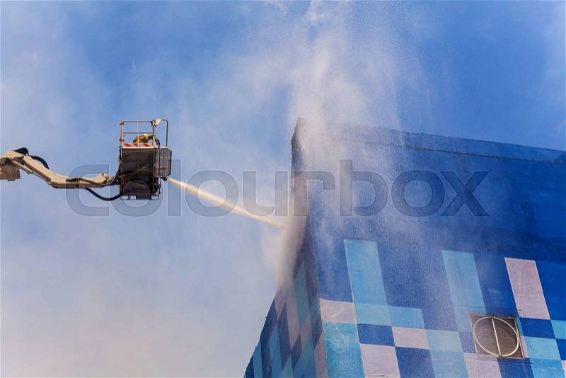 Firefighters in action, Fireman on an extended boom fighting a fire with a water hose , stock photo