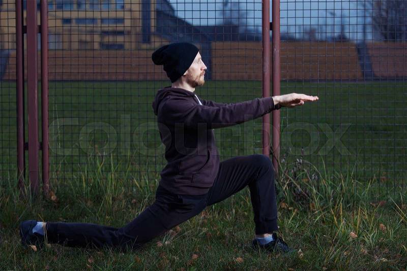 Street workout - athlete man performing frontal lunge exercise on the grass, stock photo