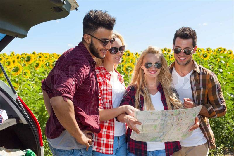 People group looking road map standing sunflowers field outdoor, two couple near car summer day holiday trip, stock photo