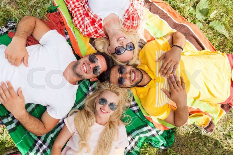 Happy people group young friends lying down on picnic blanket outdoor, two couple summer sunny day smile top angle view, stock photo