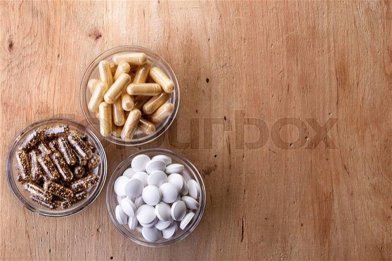 Bowls of various dietary supplements on wooden background. From top view, stock photo