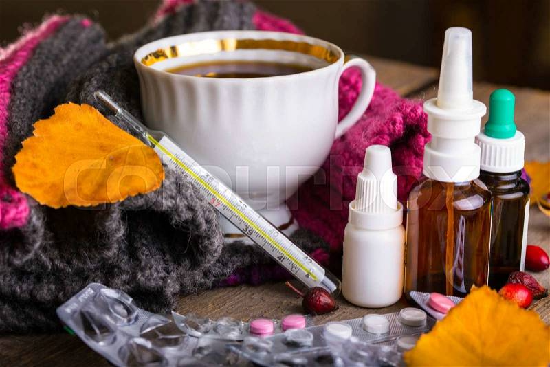 Fall and health care. Cold - cup of tea, pills and thermometer on a wooden background , stock photo