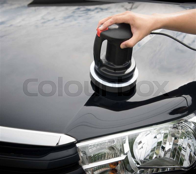 Polishing the black car with polish machine in the garage, stock photo