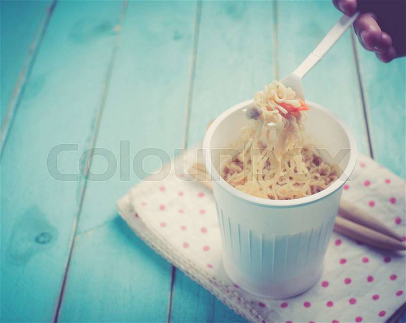 Concept of instant food,Instant noodle cup on blue wood table,vintage color toned image, stock photo