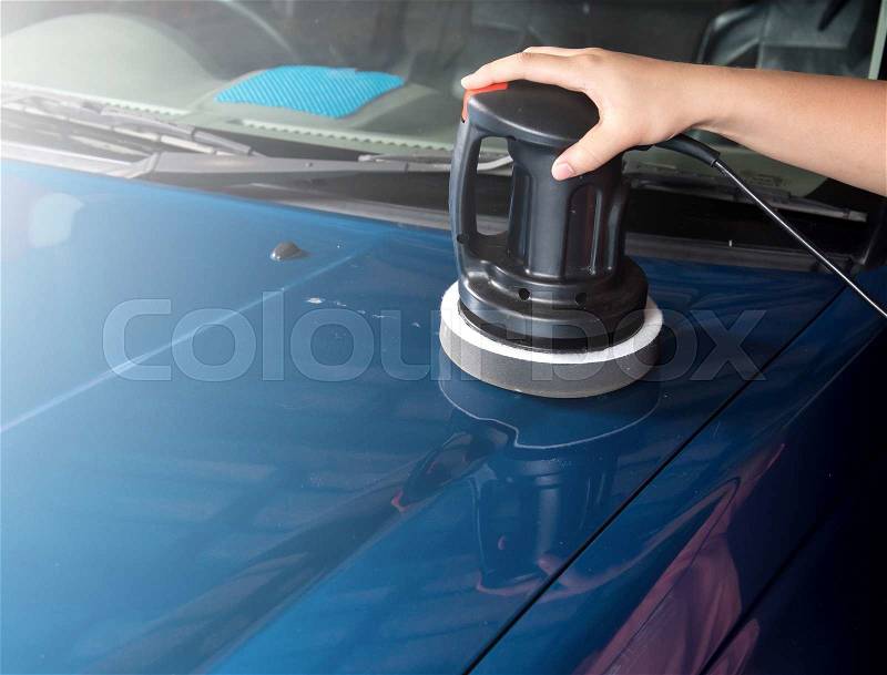 Polishing the blue car with polish machine in the garage, stock photo
