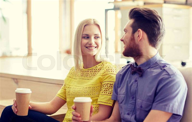 Business, startup, people and communication concept - happy man and woman drinking coffee and talking in office, stock photo