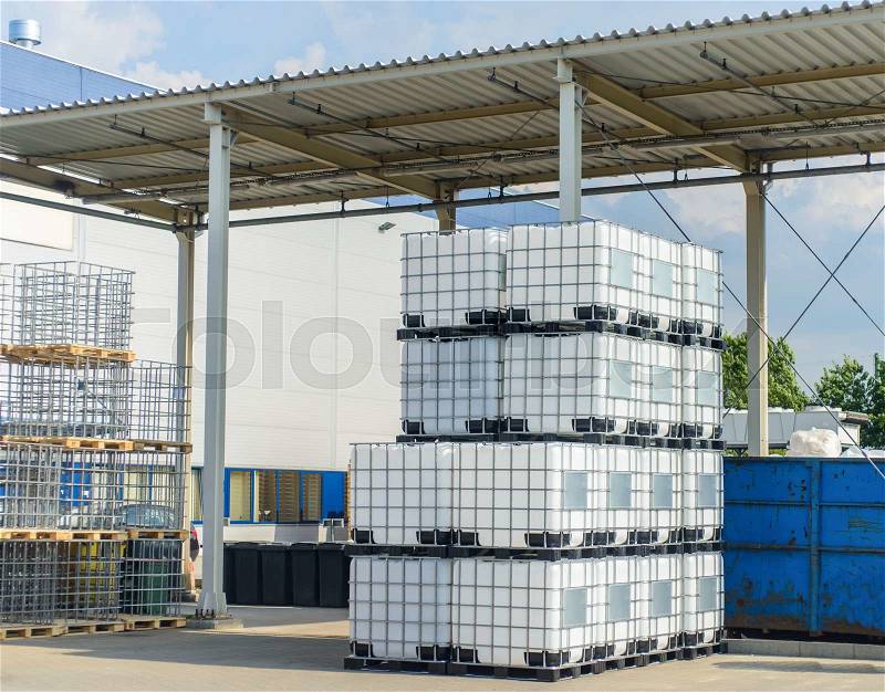 Packed pallets IBC conteiner of retail goods standing outdoors at a large modern warehouse in summer sun, stock photo