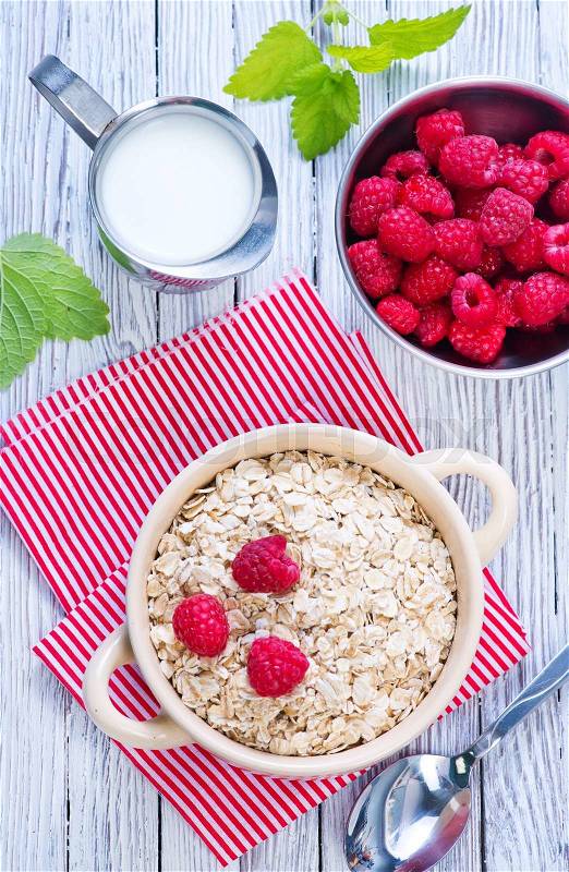 Oat flakes with raspberry in bowl and on a table, stock photo
