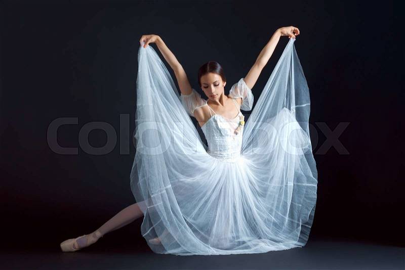 Portrait of the classical ballerina in white dress on the black background, stock photo