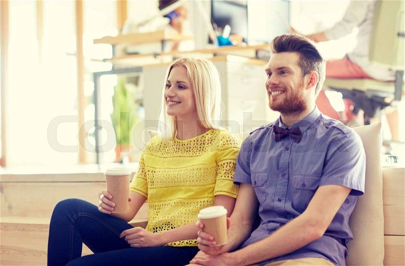 Business, startup, people and communication concept - happy man and woman drinking coffee in office, stock photo