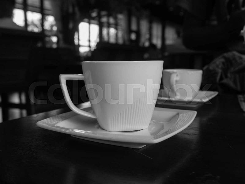 White cup of coffee on the wooden table in cafe restaurant . Black and White picture, stock photo