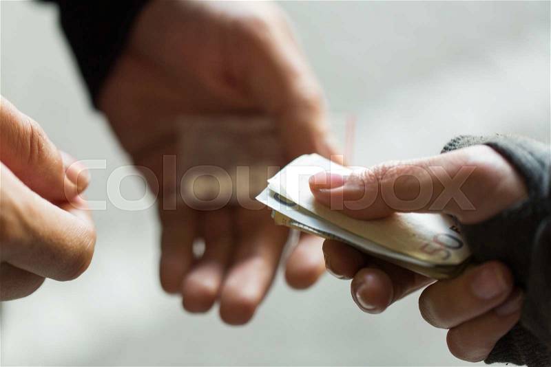 Drug trafficking, crime, addiction and sale concept - close up of addict with money buying dose from dealer on street, stock photo