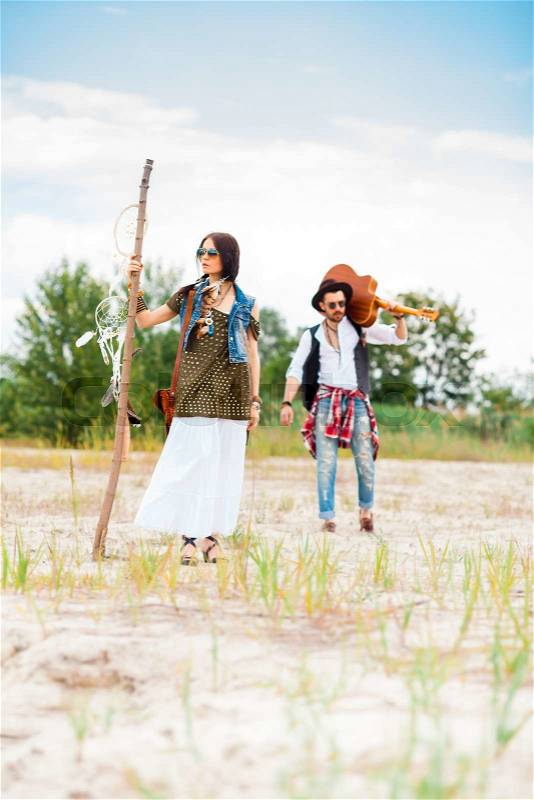 Man with guitar and woman as boho hipsters against blue sky, stock photo