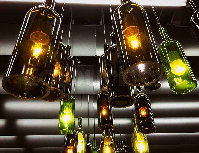 Magnificent retro light lamp decor made of the wine bottles. Toned, stock photo