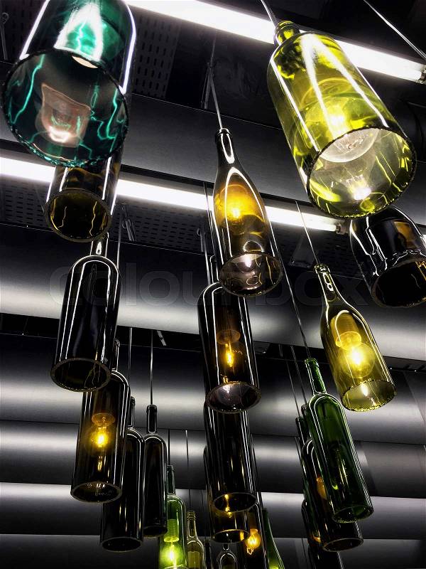Magnificent retro light lamp decor made of empty wine bottles. Toned, stock photo