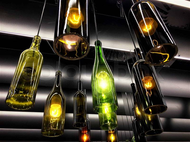 Beautiful retro light lamp decor made of empty wine bottles. Toned, stock photo