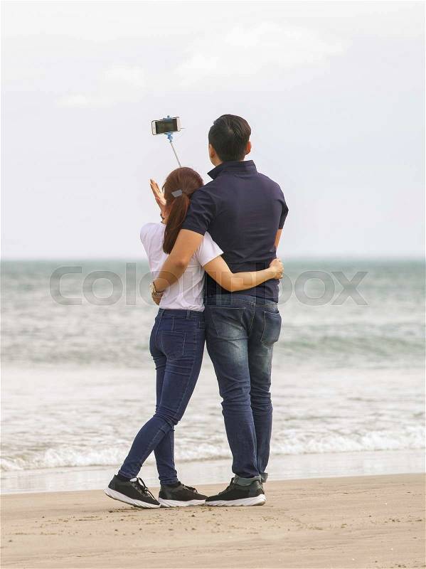 Young people using a selfie stick at the China Beach of Danang in Vietnam, stock photo