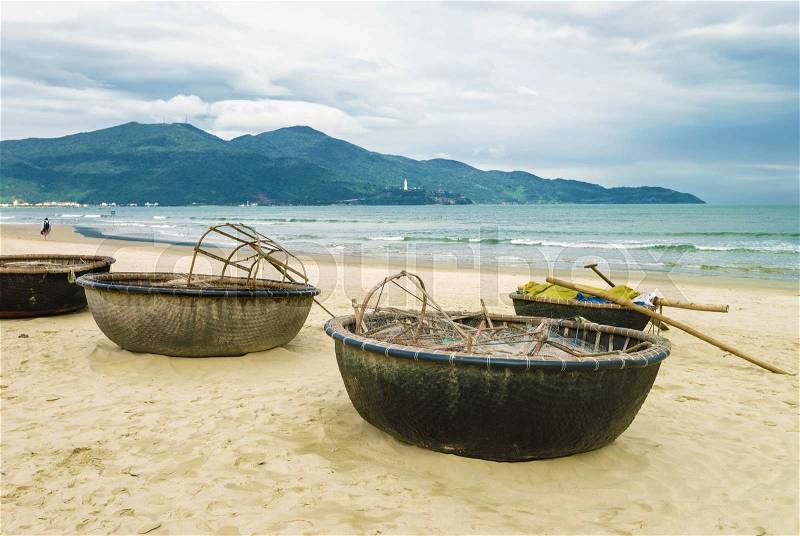 Bamboo waterproof round fishing boat on the China Beach in Danang, in Vietnam. It is also called Non Nuoc Beach. South China Sea and Marble Mountains on the background, stock photo