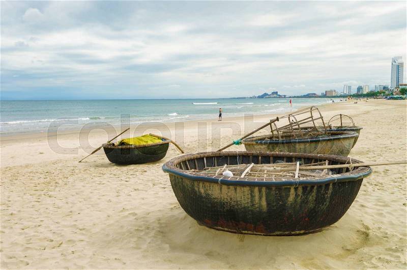 Bamboo waterproof round fishing boats at the China Beach, in Danang in Vietnam. It is also called Non Nuoc Beach. South China Sea and Marble Mountains on the background, stock photo