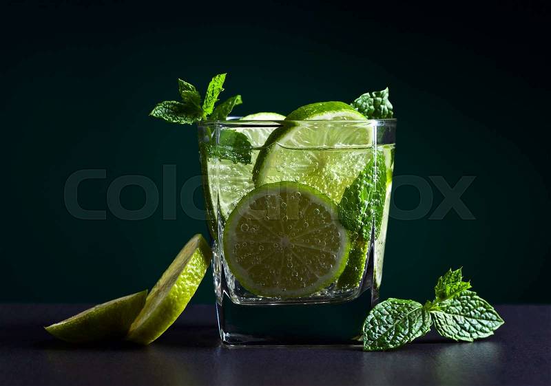 cocktail with lime , ice and peppermint leaves on a black table, stock photo