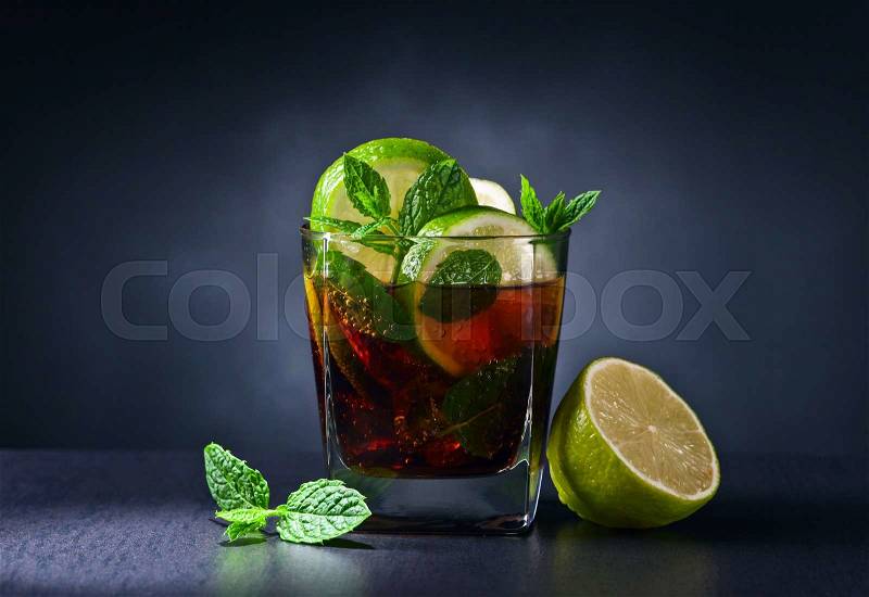 cocktail with cola, lime and peppermint on a black table, stock photo
