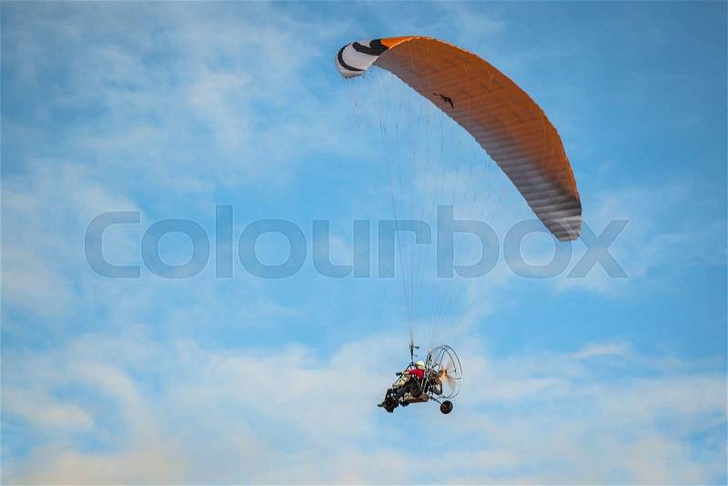 The motorized hang glider in the blue sky, stock photo
