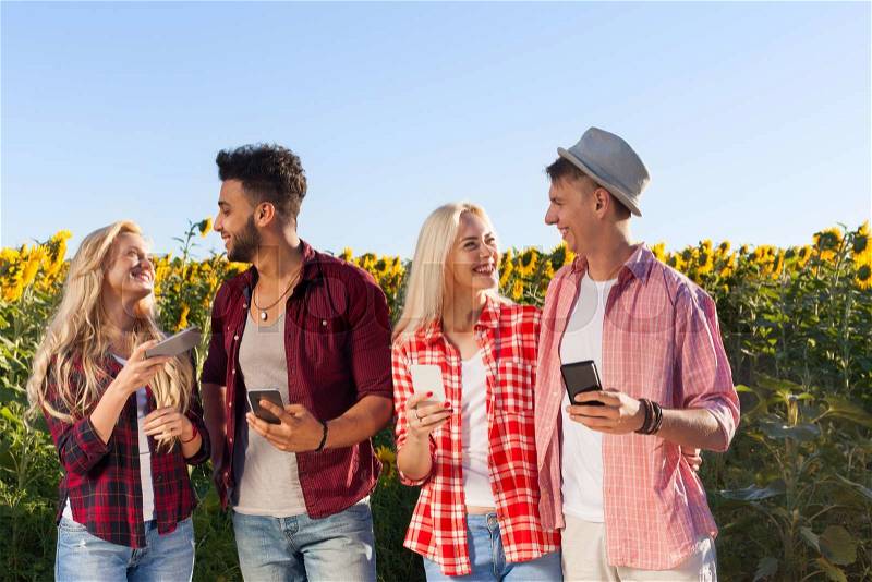 People using smart phone chatting group friends outdoor countryside sunflowers field blue sky two couple messaging internet happy smile summer sunny day, stock photo