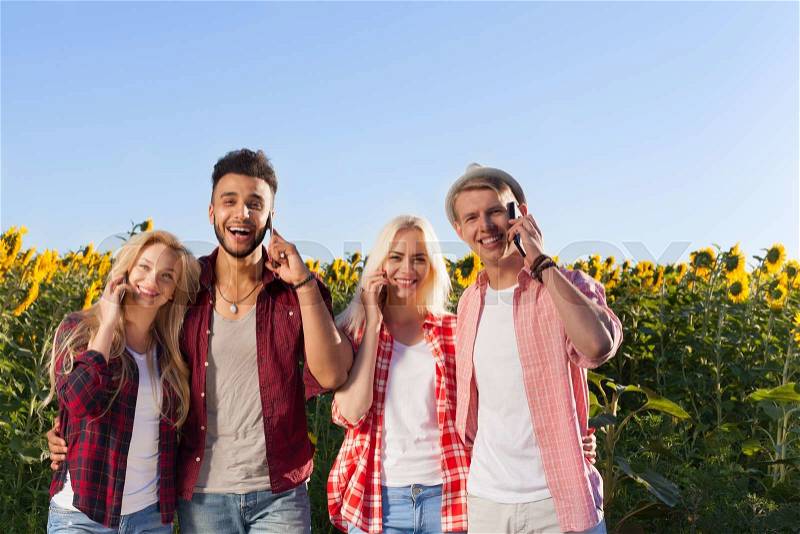 People smart phone call group friends outdoor countryside sunflowers field blue sky two couple happy smile talking cell, summer sunny day, stock photo