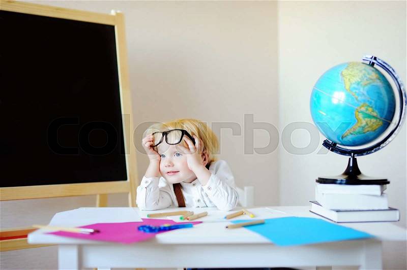 Portrait of tired little boy at school workplace. Back to school concept, stock photo