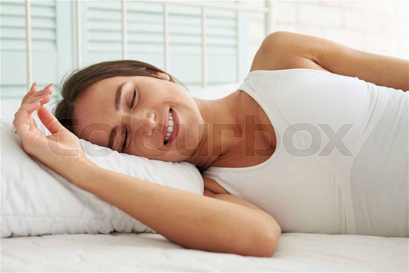 Beautiful brunette has a good sleep in her bed early in the morning at home, stock photo