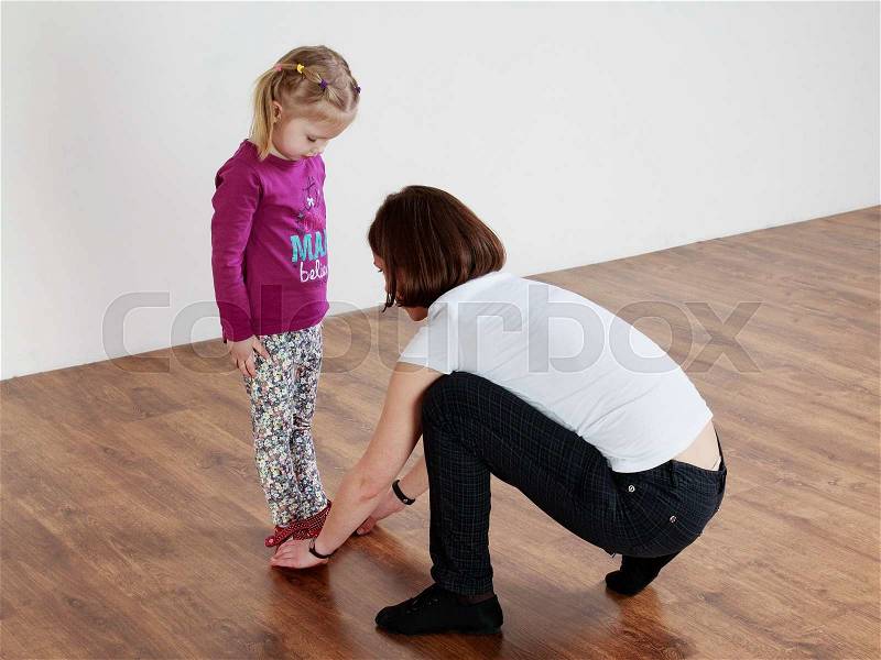 Children activity. Trainer showing leg position to a little girl , stock photo