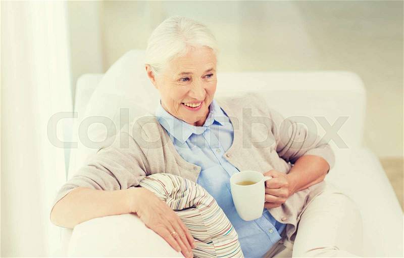 Age, drink and people concept - happy smiling senior woman with cup of tea at home, stock photo