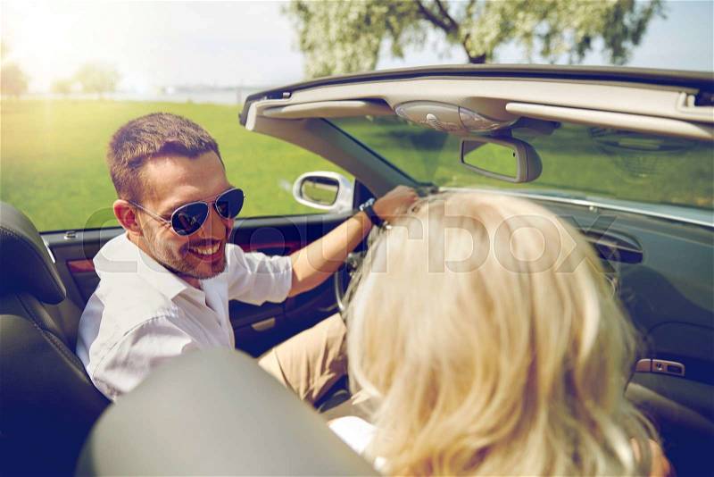Leisure, road trip, dating, couple and people concept - happy man and woman driving in cabriolet car outdoors, stock photo